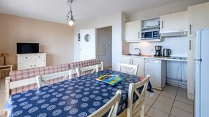 Un espacio habitable funcional con comedor, kitchenette y televisor.