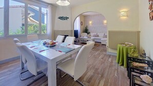 Ein Essbereich mit Tisch für zwei Personen, einer Couch und einem grünen Tisch mit Buddha-Statuen.