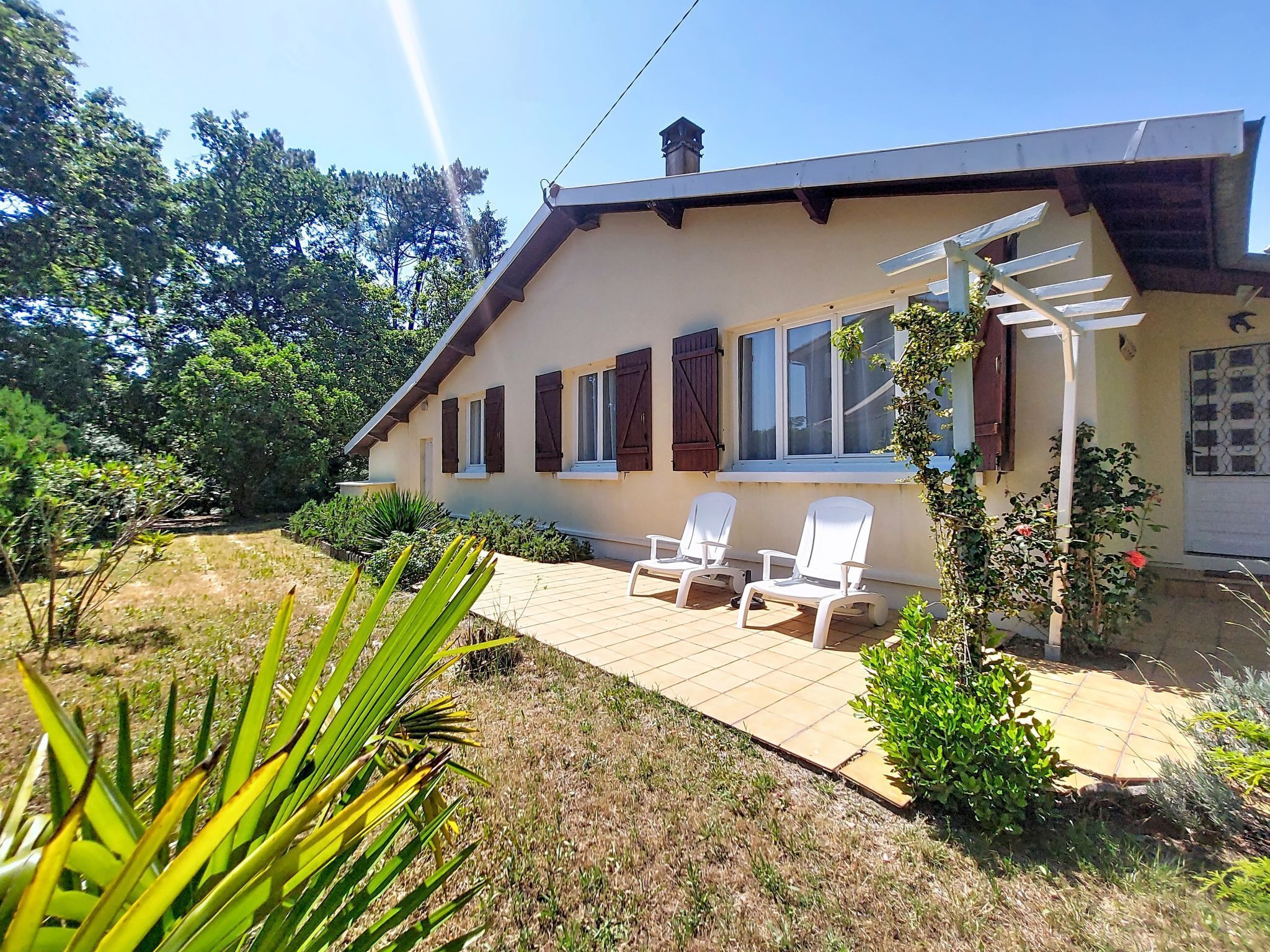 Una casa con un patio, sillas blancas y jardín.