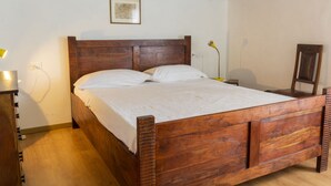 Un lit en bois avec une tête de lit, une lampe de chevet et un tableau encadré accroché au mur.