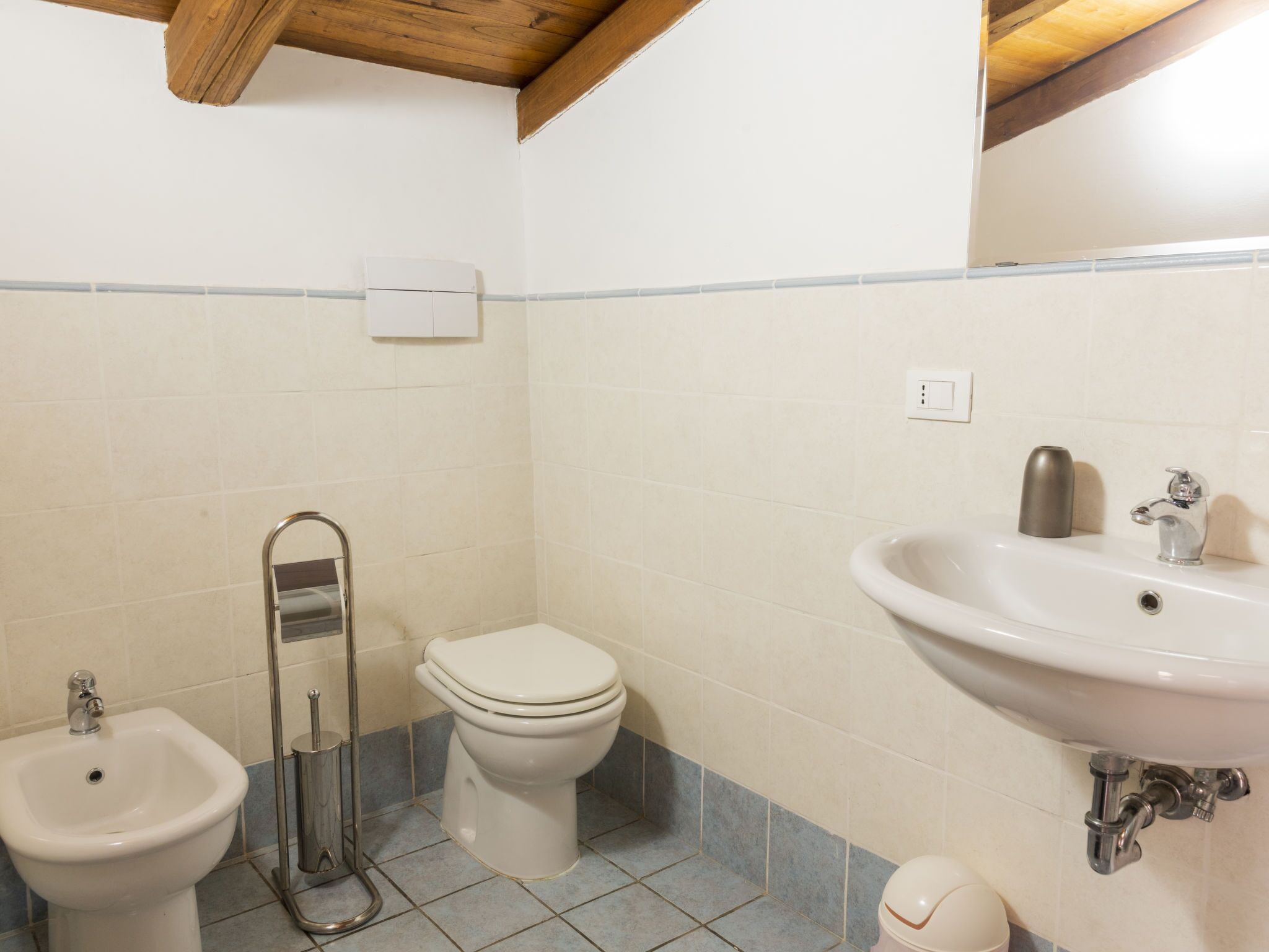 A bathroom with a toilet, bidet, sink, and a mirror.