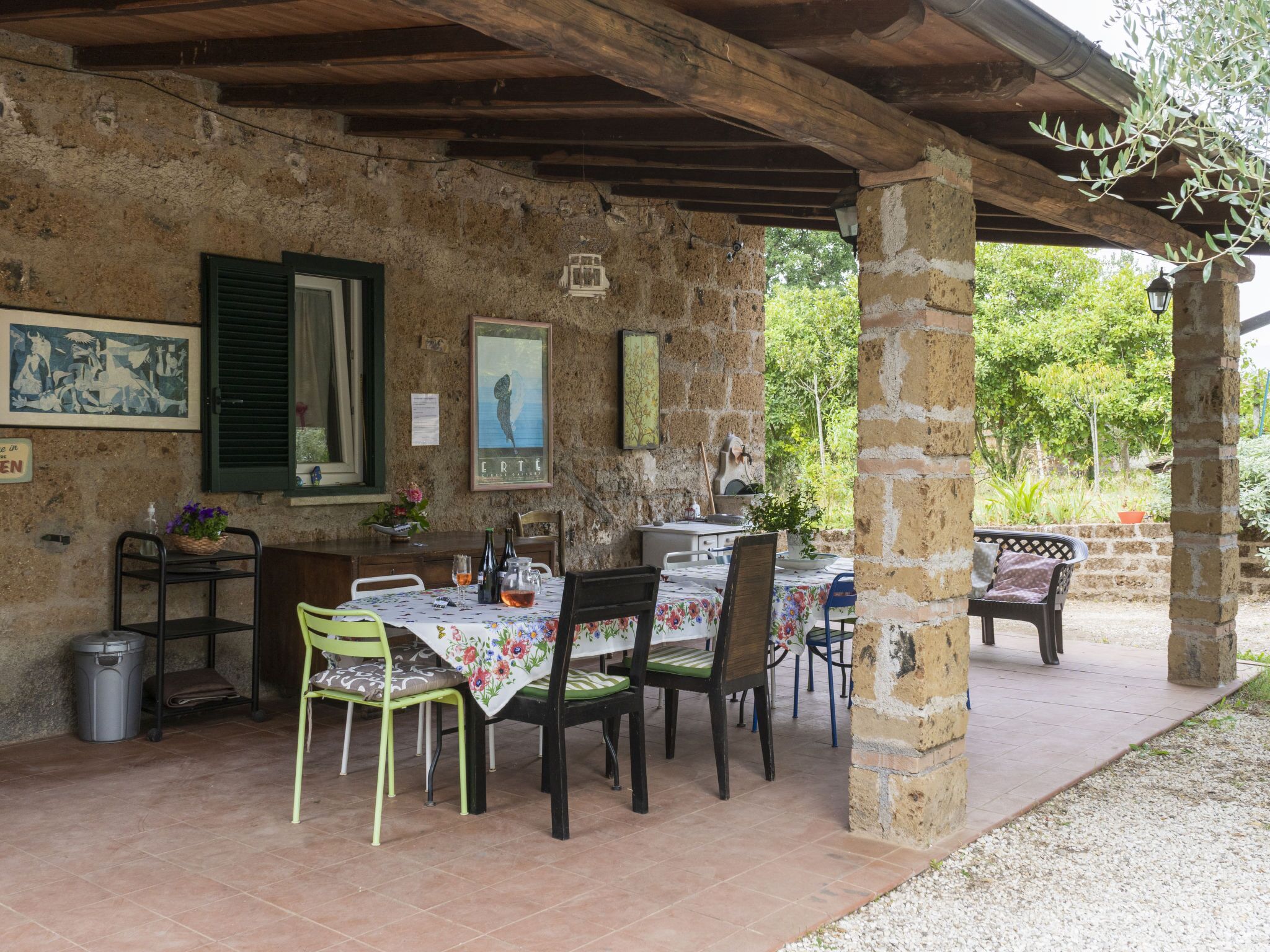 An outdoor dining area with rustic stone walls, wooden beams, and a tiled floor.