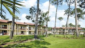 Un hôtel à plusieurs étages, doté de balcons et d’une pelouse bien entretenue.