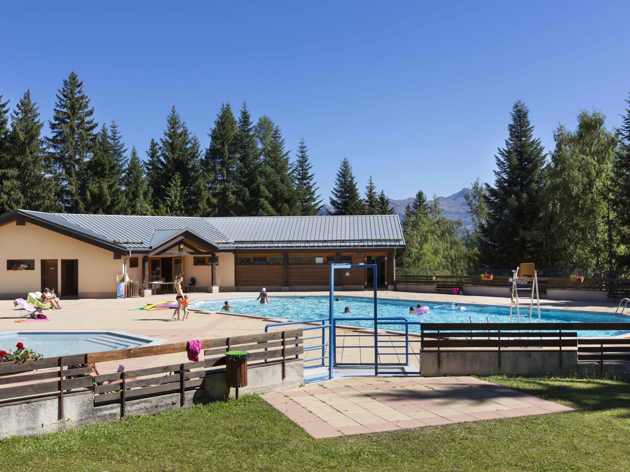 Un’area piscina con un edificio sullo sfondo, circondata da alberi.