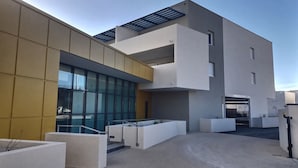 A modern building with a flat roof, large windows, and a concrete courtyard.