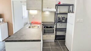 A compact kitchen with a built-in oven, a sink, and a small refrigerator.