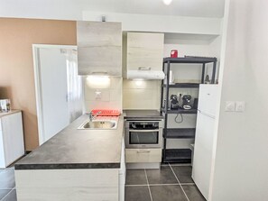 A compact kitchen with a built-in oven, a sink, and a small refrigerator.
