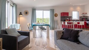 Un salon moderne avec un canapé, une table à manger pour deux personnes et un coin cuisine doté de meubles rouges.