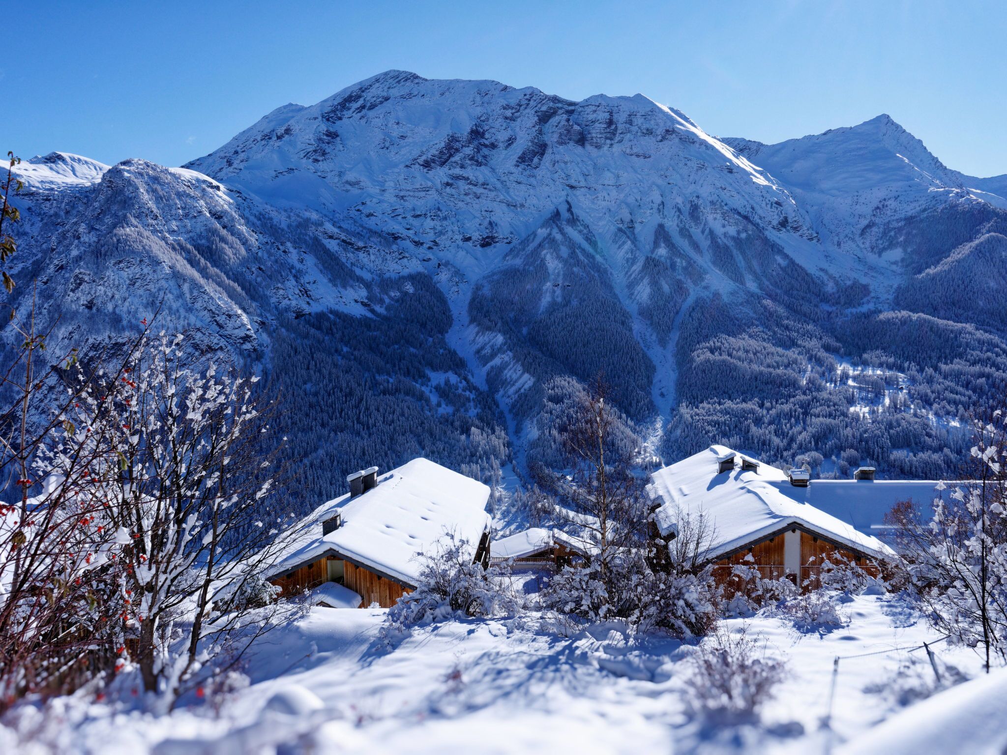 Un paisaje montañoso nevado con dos cabañas de madera.