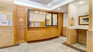 A reception area with a wooden reception desk, a mirror, and a stone-tiled floor.