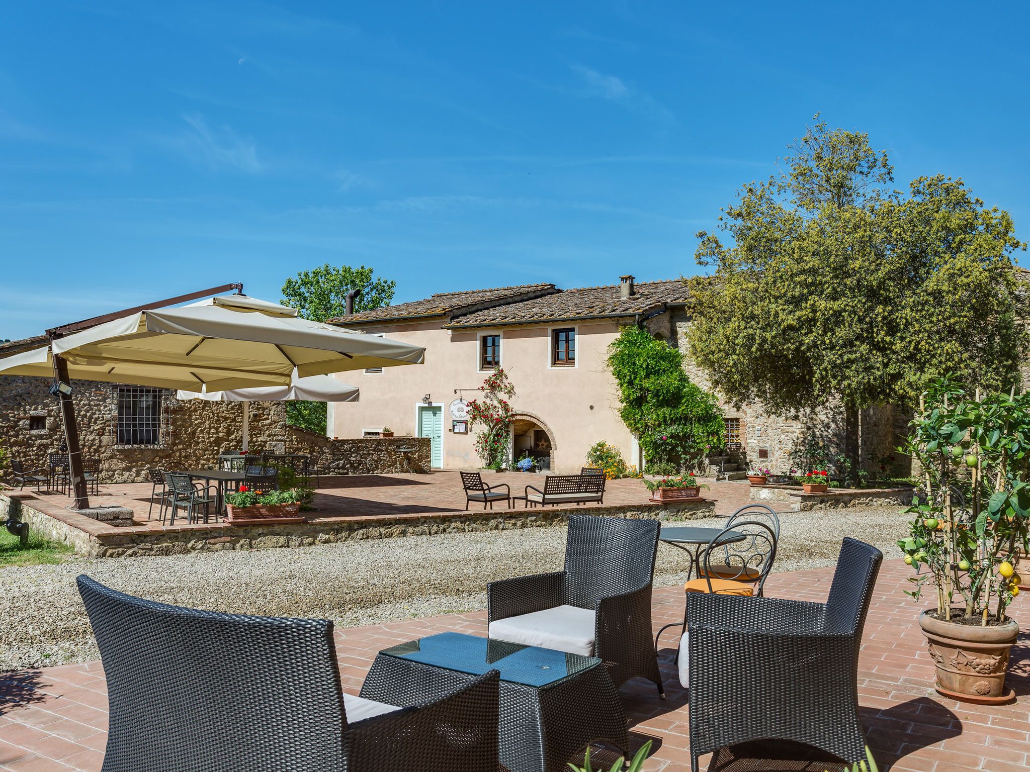 Une terrasse extérieure avec des meubles en osier, un mur en pierre et un bâtiment doté d’un toit en tuiles.