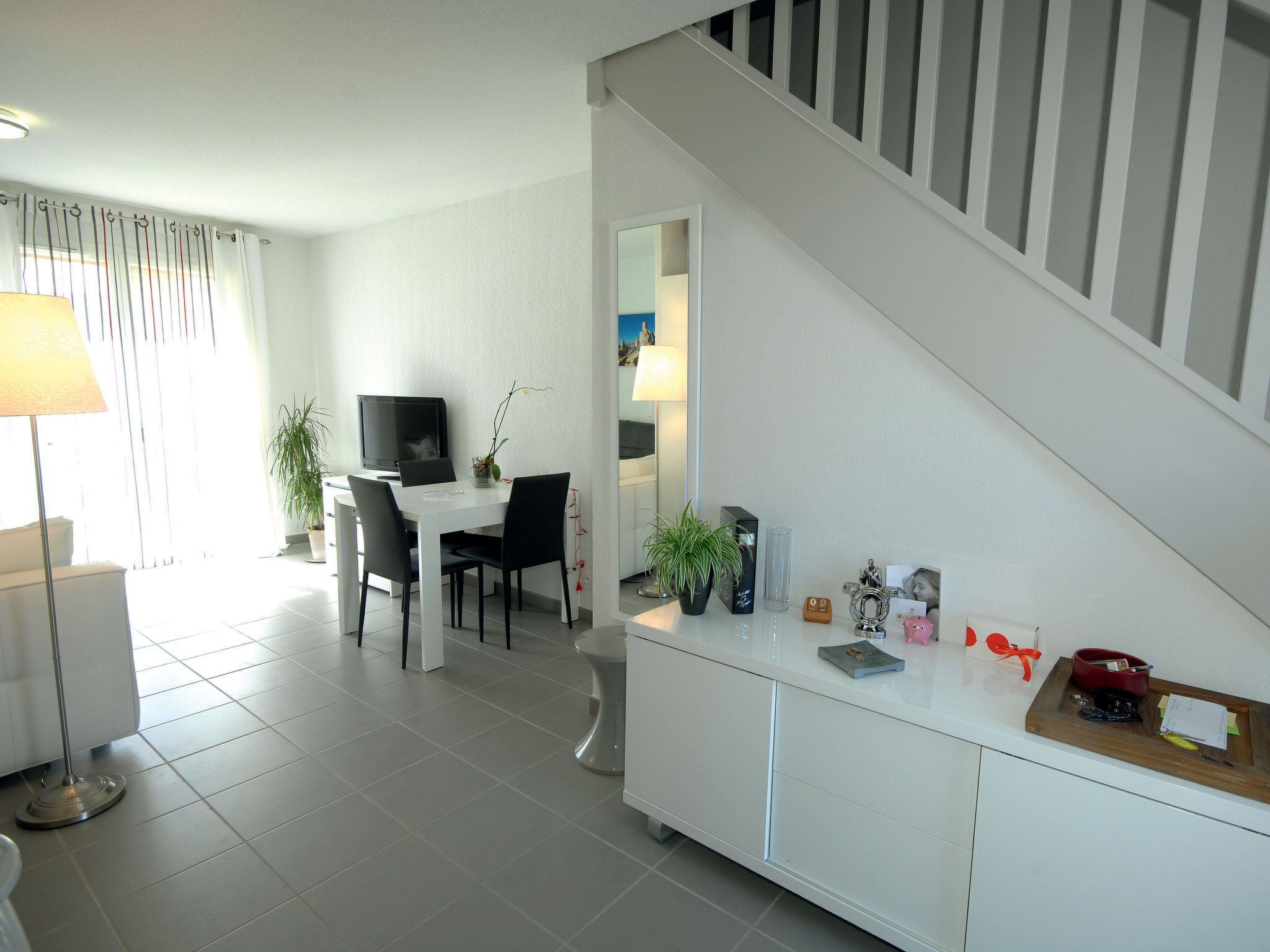 Un salon moderne comprenant un coin repas, un escalier et une cuisine.