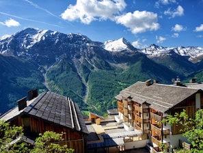 Un albergue de montaña con arquitectura de madera, varios balcones y vistas a montañas nevadas.