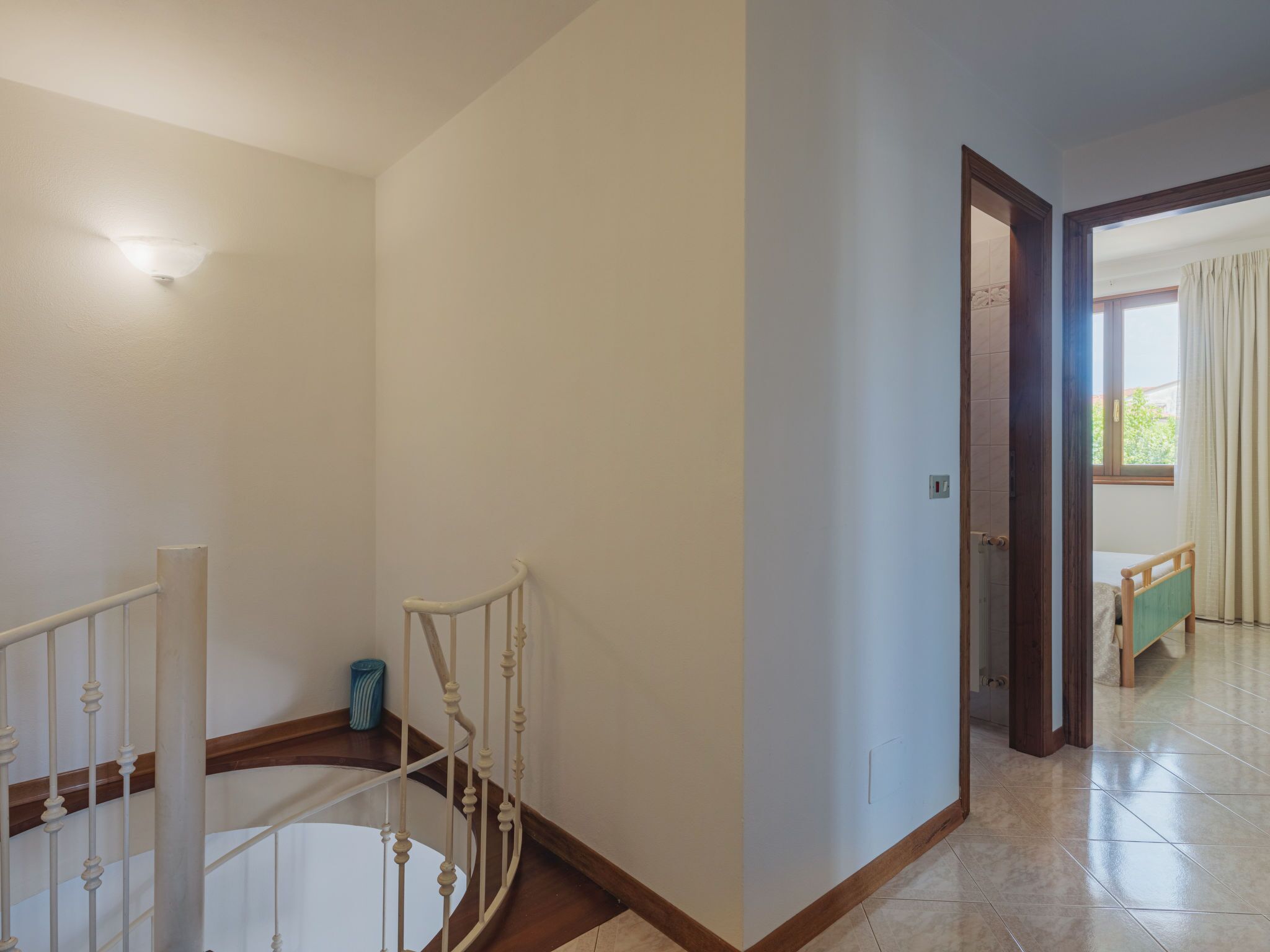 Une pièce spacieuse avec un escalier, une petite table et une fenêtre avec des rideaux.
