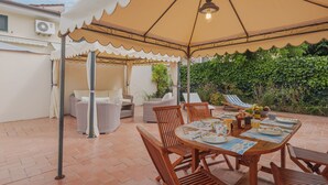 A covered outdoor patio with a table set for dining, wicker furniture, and a hanging light fixture. - Vacation home Rosa by Interhome (Lido di Camaiore)
