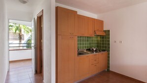 Et køkken med træskabe, en grøn backsplash og udsigt til en balkon med palmer.