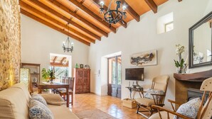 A spacious living room with a high wooden ceiling, a fireplace, and a television. - Son Catlar by Interhome (Inca)