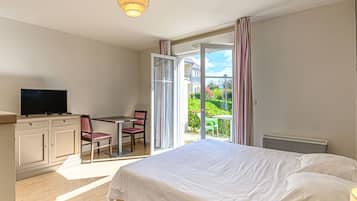 Une chambre d’hôtel comprenant un lit, un bureau avec une chaise, une télévision et une vue sur l’extérieur.