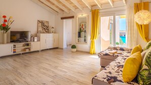 A modern living room with a wooden ceiling, a sofa with yellow cushions, a TV on a white cabinet, and a large mirror. - Apartment Yoko by Interhome (Ses Salines)