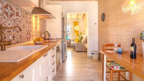 A modern kitchen with a wooden countertop, white cabinets, and a stone wall. - Apartment Yoko by Interhome (Ses Salines)