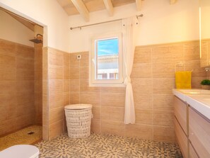 Une salle de bain avec une douche, une fenêtre donnant sur un beau paysage, un lavabo et un carrelage décoratif.