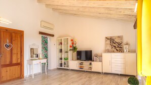 A modern living room with a wooden floor, white furniture, a TV, and a decorative plant. - Apartment Yoko by Interhome (Ses Salines)