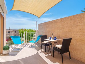Une terrasse avec une table et des chaises, un pot de fleurs et une vue sur des bâtiments en arrière-plan.