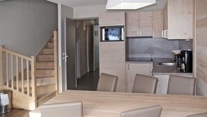 A modern kitchen with wooden cabinets, a built-in oven, and a coffee maker.