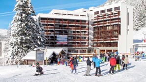 A multi-story hotel with a ski resort in the background.