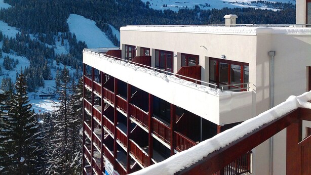 A modern building with multiple balconies overlooking a snowy mountain landscape.