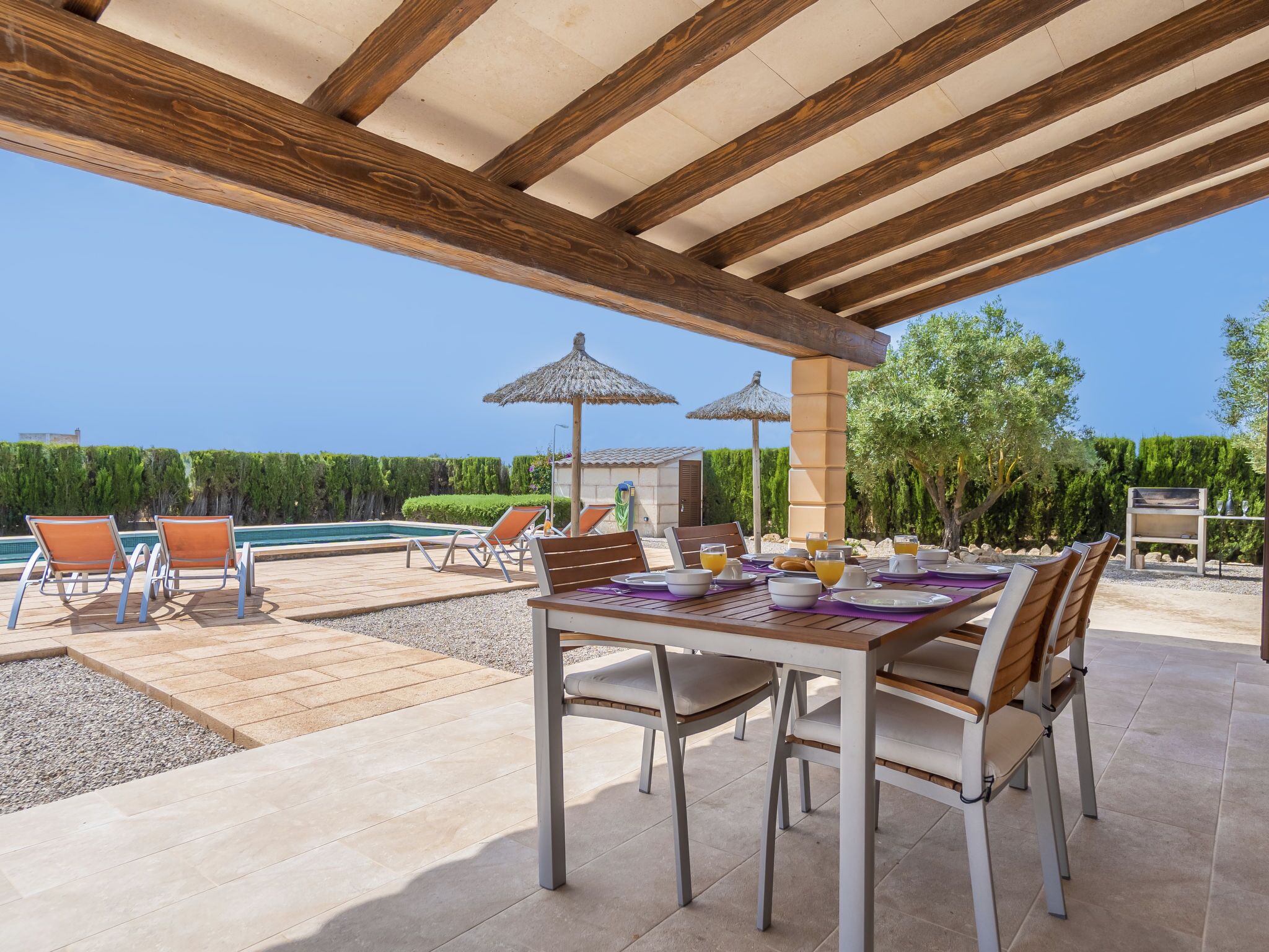 An outdoor dining area with a pool, lounge chairs, and umbrellas.