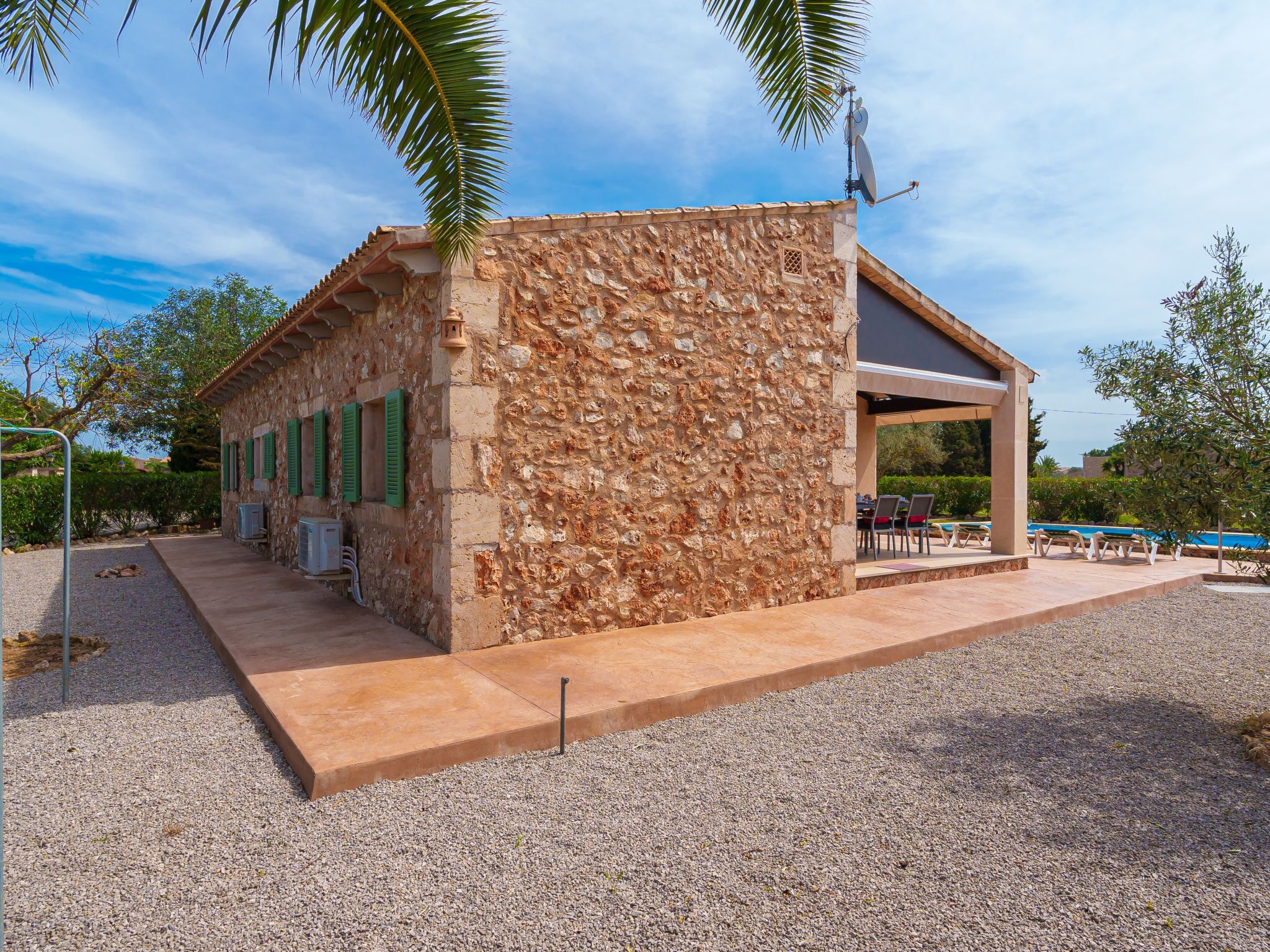 A stone building with a covered patio area, a pool, and outdoor seating.