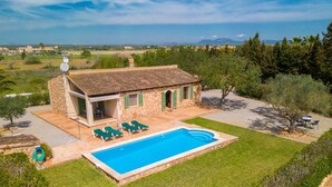 Uma villa com piscina, relvado verde e vista para o campo.