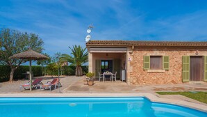 A poolside area with lounge chairs, a table, and a thatched umbrella. - Vacation home Marina by Interhome (Sa Rápita)