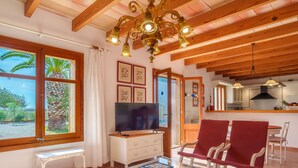 A spacious living room with a TV, red chairs, a glass coffee table, and a wooden ceiling. - Vacation home Marina by Interhome (Sa Rápita)
