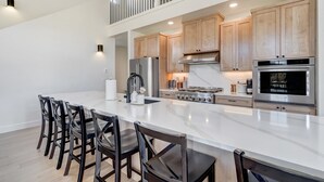 Una cocina moderna con una isla grande, armarios de madera, electrodomésticos de acero inoxidable y un entresuelo.