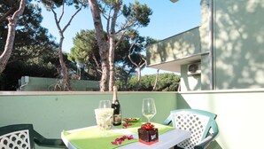An outdoor table with a white tablecloth, two chairs, a bottle of champagne, and a glass of white wine. - Veranda by Interhome (Rosolina Mare)