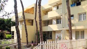 A multi-story hotel with balconies, a white picket fence, and potted plants. - Veranda by Interhome (Rosolina Mare)