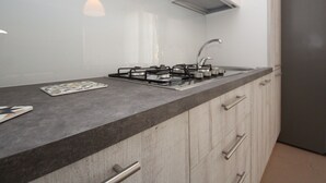 A modern kitchen with a gas stove, stainless steel sink, and wooden cabinets. - Veranda by Interhome (Rosolina Mare)
