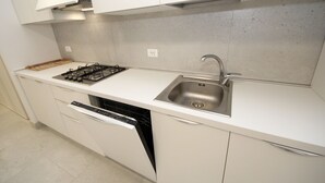 A modern kitchen with white cabinetry, a stainless steel sink, a gas stove, and a dishwasher. - Marcello by Interhome (Rosolina Mare)