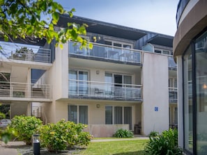 Un edificio de varios pisos con balcones, un letrero de estacionamiento y un césped bien cuidado.