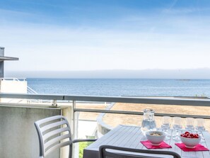 Un balcón con una mesa lista para comer, con vista al mar.