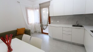 Une cuisine moderne avec des meubles blancs, un évier et un coin repas comprenant une table et des chaises.