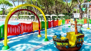 Ein Wasser-Spielbereich für Kinder mit einer schiffsförmigen Wasserspielsäule und bunten Spielgeräten.