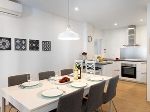 A modern kitchen with white cabinets, a stainless steel range hood, and a dining area with a white table set for four. - La Najarra by Interhome (Almuñécar)