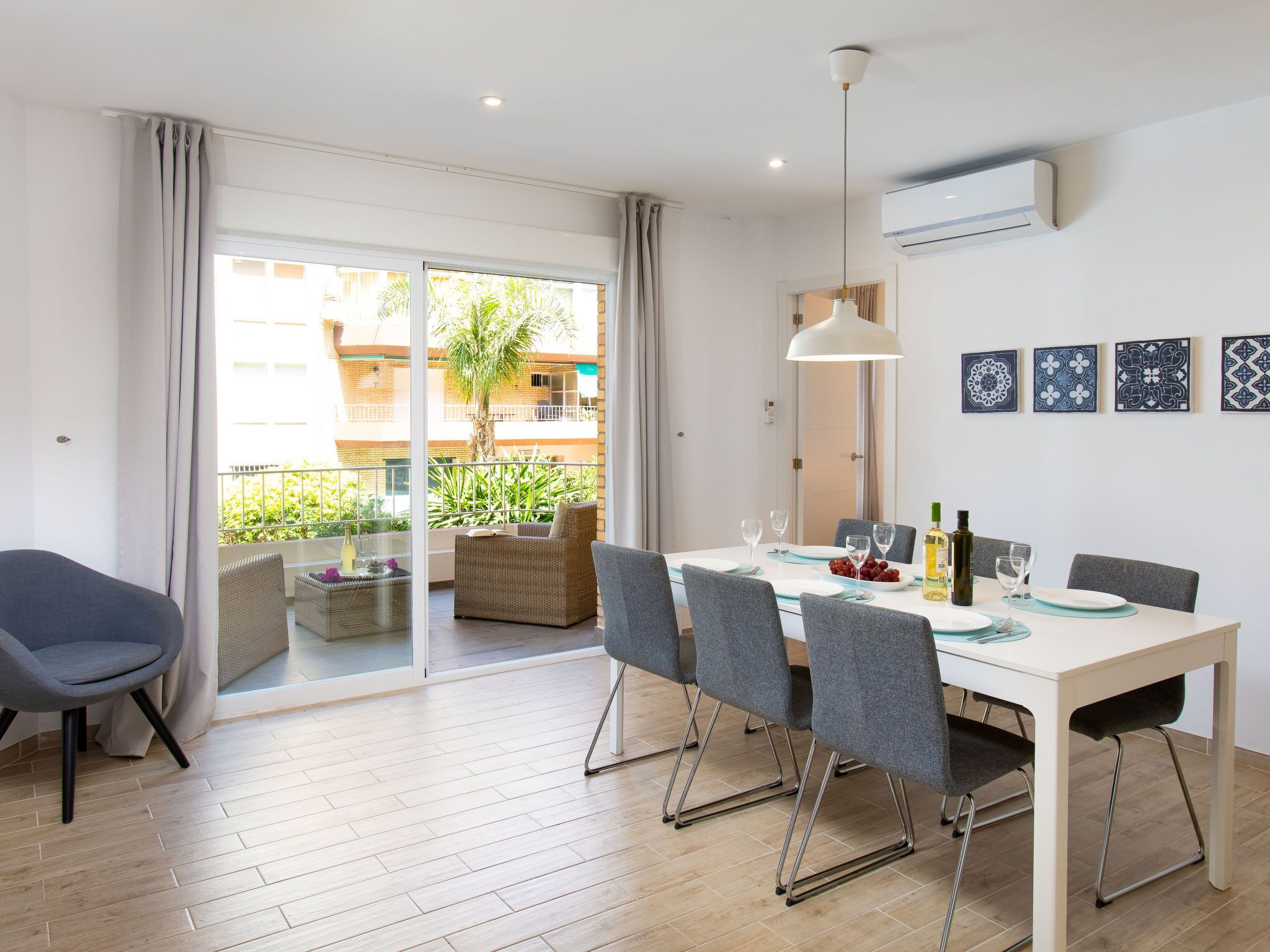 A dining area with a table set for four, a sofa, and a chair.