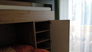 Un llit superposat amb un llit inferior i un armari amb moltes prestatgeries.
