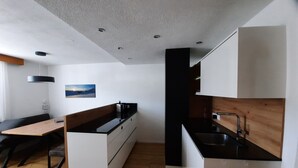 Una cuina moderna amb armaris blancs, tauleig de fusta i un rentaplat de color negre.