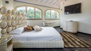 A bedroom with a large bed, a TV mounted on the wall, and a window with a view of trees. - Appendino by Interhome (Asti)