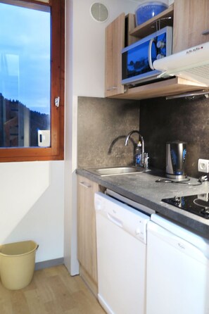 Una cocina con ventana, un lavamanos, lavavajillas y estufa.
